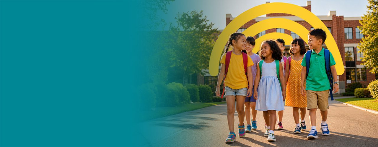 Group of smiling school children walking together outside a school building.